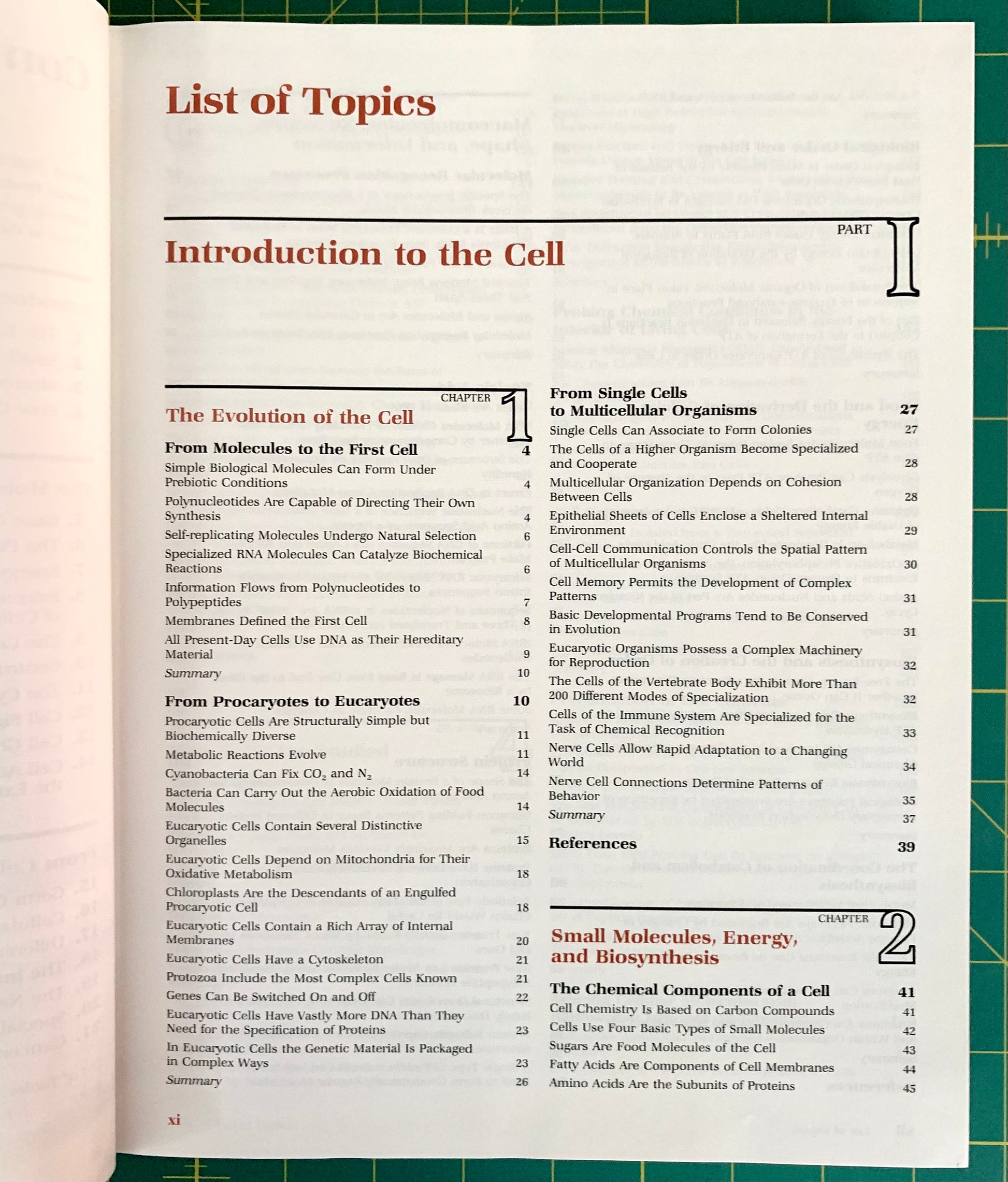 An open book showing the 'List of Topics' page from its front matter, with printed text and page numbers on cream paper. A green cutting mat is visible along the right edge of the book.
[additional_image_link]