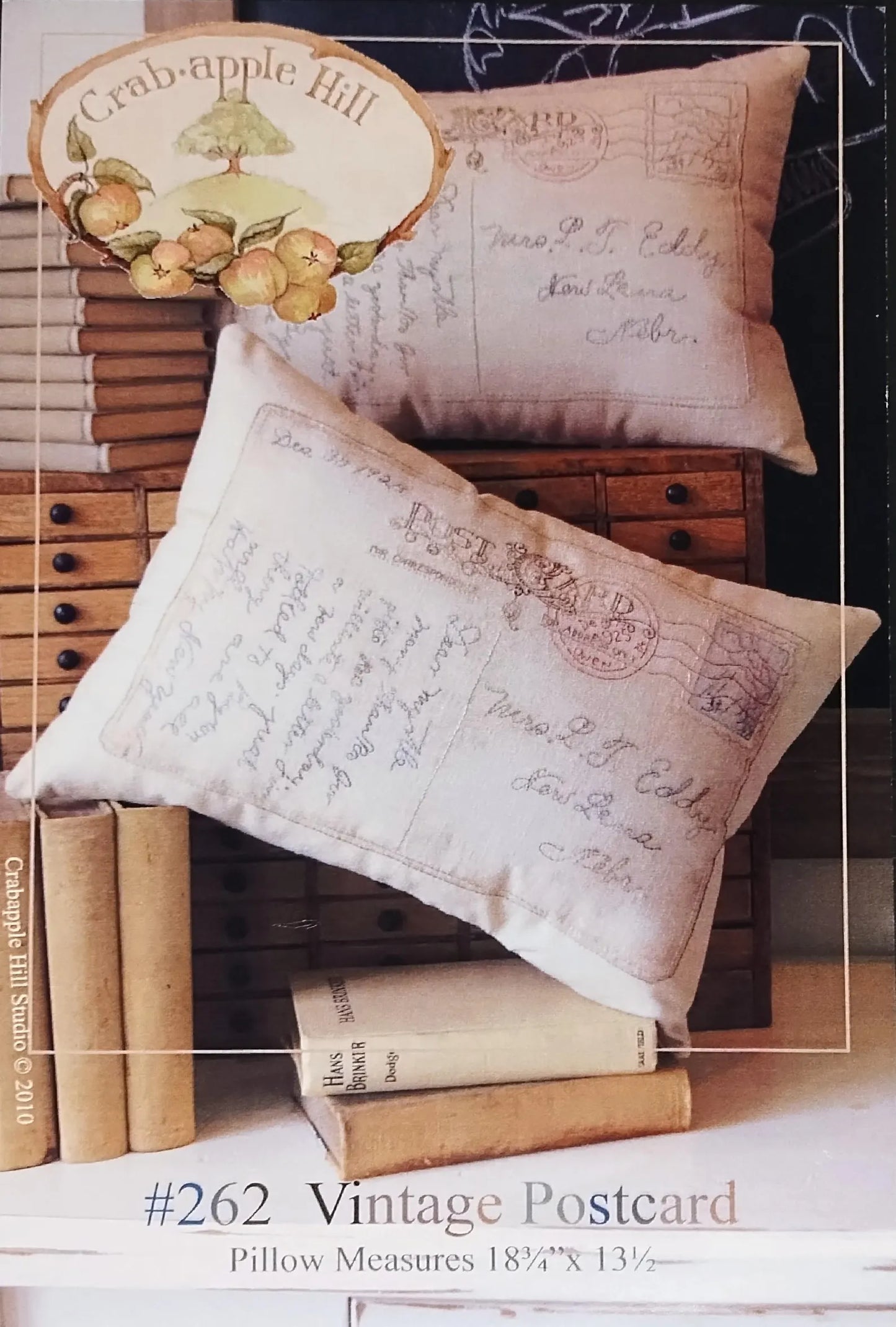 Two vintage-style postcard pillows displayed on stacked antique books, with a decorative sign reading 'Cranberry Hill' in the background. Text at the bottom identifies the item as a '#262 Vintage Postcard Pillow' with measurements.
Photo by SamSarah Studio Designs [additional_image_link]