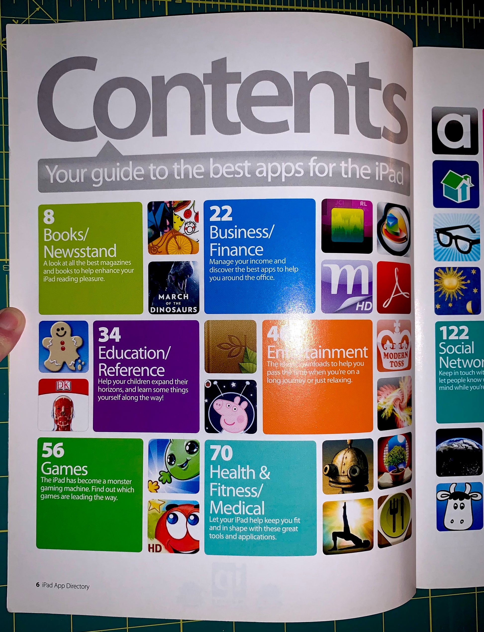 An open printed guide or booklet showing a colorful iPad apps contents page with large 'Contents' heading and multiple colored app tiles, photographed against a green cutting-mat background.
[additional_image_link]