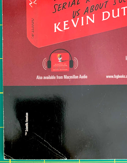 A book cover for 'Serial Killer: What About You' by Kevin Dutton, featuring a red upper section with white and black text, a headphone graphic, and a large black lower section. The book is photographed on a green cutting mat.
[additional_image_link]