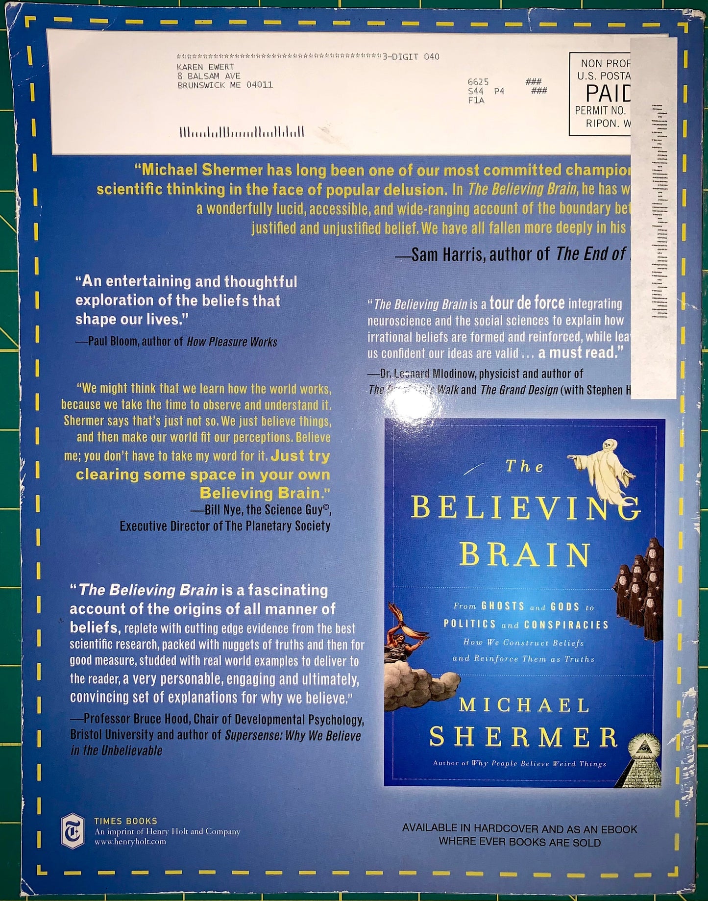 A book cover for 'The Believing Brain' by Michael Shermer, displayed against a blue-green grid background with printed review quotes and publisher text. The cover features a white title area, a blue lower section, and an illustration of a bird flying over a landscape.
[additional_image_link]