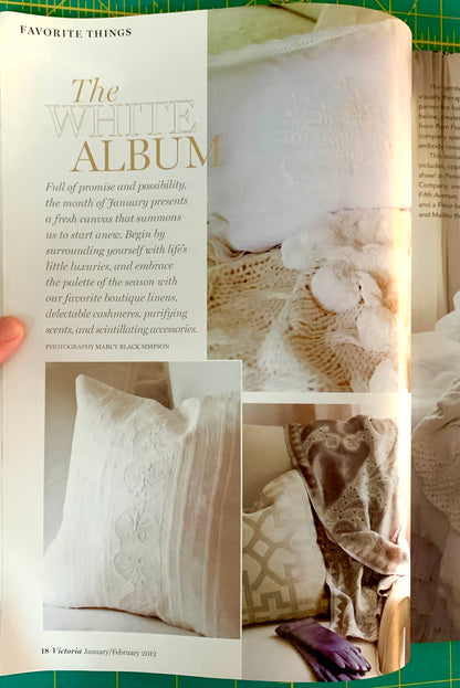 An open magazine or book page spread titled 'The White Album' with fashion photography of white and beige garments, shown against a green cutting mat background.
[additional_image_link]
