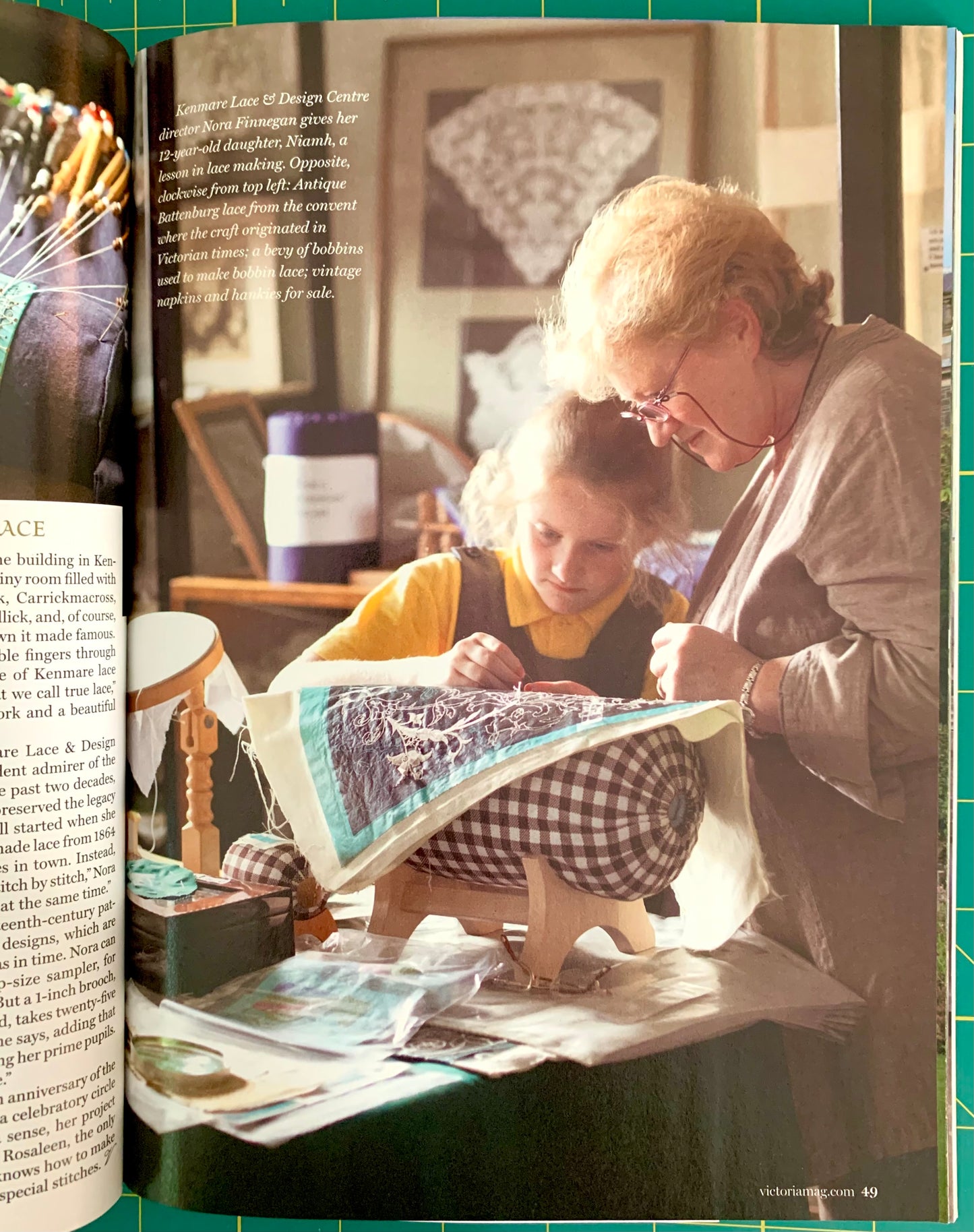 An open book showing a color photograph of an elderly woman and a child sewing a patterned quilt on a table, with printed text visible on both pages.
[additional_image_link]