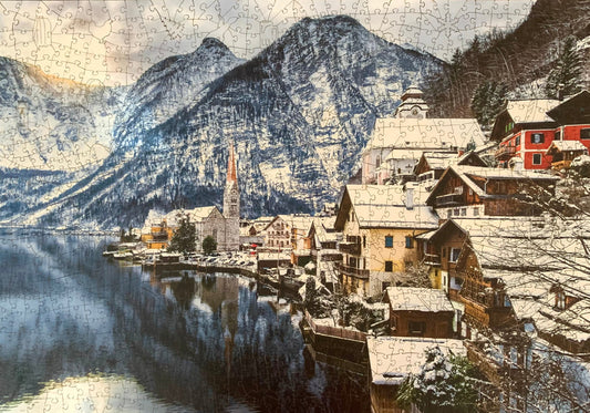 A wooden jigsaw puzzle depicting a winter scene in Hallstatt, Austria, with snow-covered houses and mountains in the background.
Photo by Karen King [image_link]