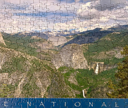 A jigsaw puzzle depicting a panoramic view of Yosemite National Park with green trees and rock formations.
Photo by Karen King [additional_image_link]