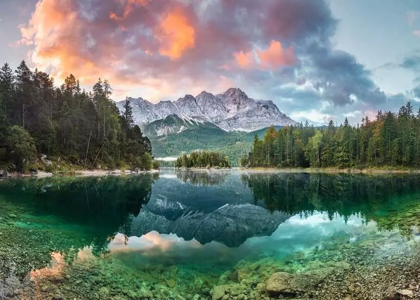 Mountain landscape with a lake and trees under a colorful sky.
Photo by Ravensburger [image_link]