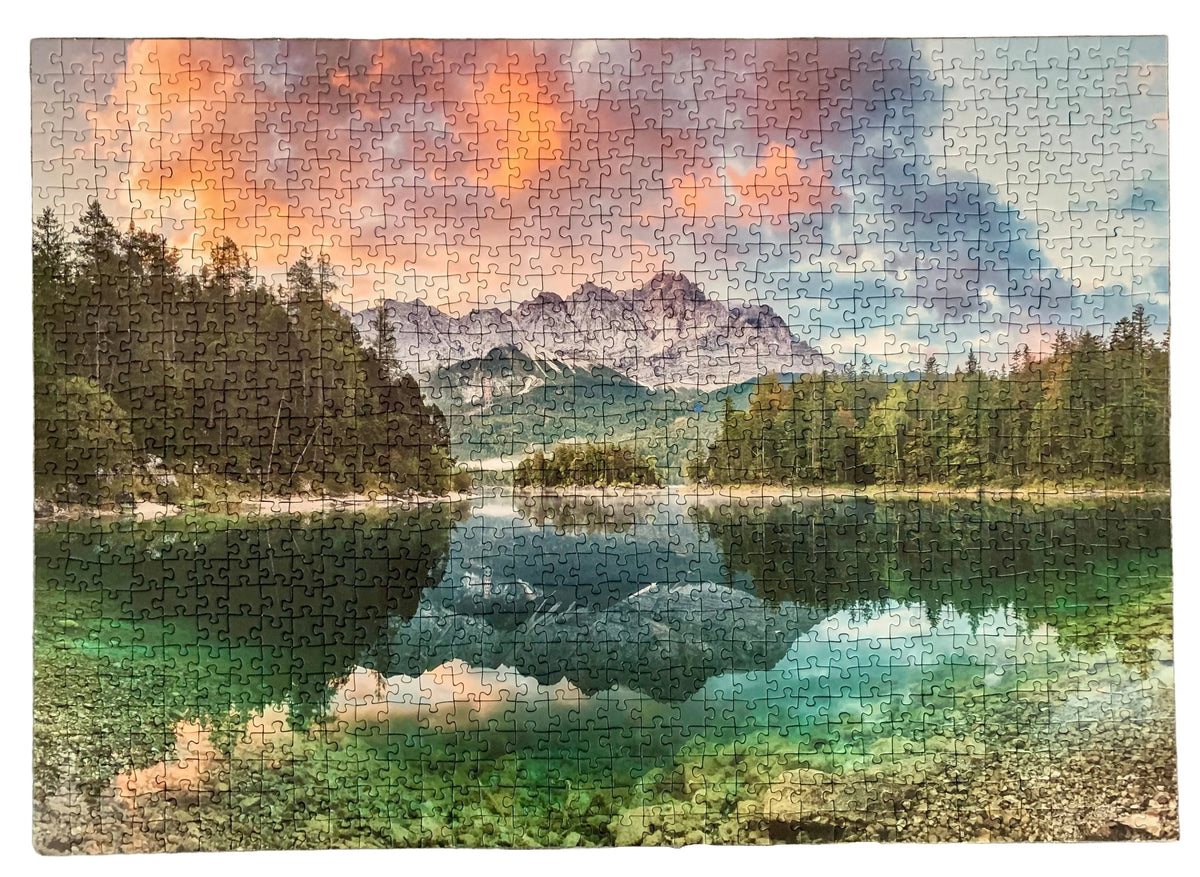 A completed jigsaw puzzle showing a scenic mountain lake landscape with pine trees, clear turquoise water, and a dramatic orange and blue sky.
Photo by Karen King [additional_image_link]