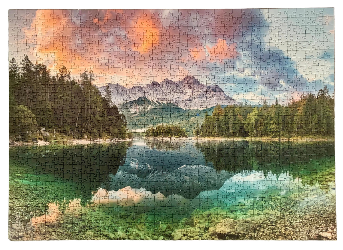A completed jigsaw puzzle showing a scenic mountain lake landscape at sunset, with colorful clouds, dark pine trees, and reflective water.
Photo by Karen King [additional_image_link]