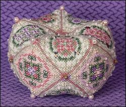 A decorative, hand-beaded biscornu with intricate floral patterns in pink, green, and gold on a purple textured background.
Photo by JustNan.com [additional_image_link]