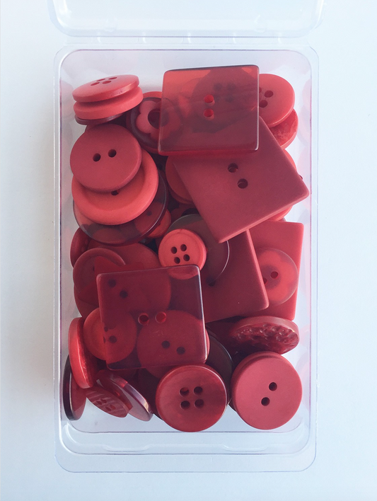 A clear plastic case containing 55 red hand-dyed buttons of various sizes, displayed in a pile.
Photo by JustAnotherButtonCompany.com [image_link]