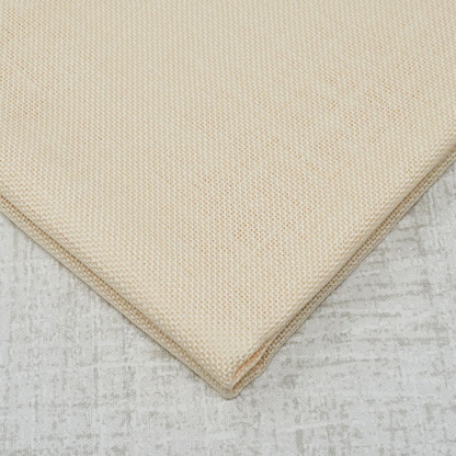 A close-up of a folded beige woven fabric, showing its fine texture and corner detail against a plain white background.
Photo by Wichelt [additional_image_link]