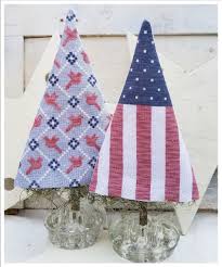 Cross stitch trees depicting a Christmas tree with red and blue checkered patterns on a white background, displayed on a small tree stand.
Photo by HelloFromLizMathews.com [additional_image_link]