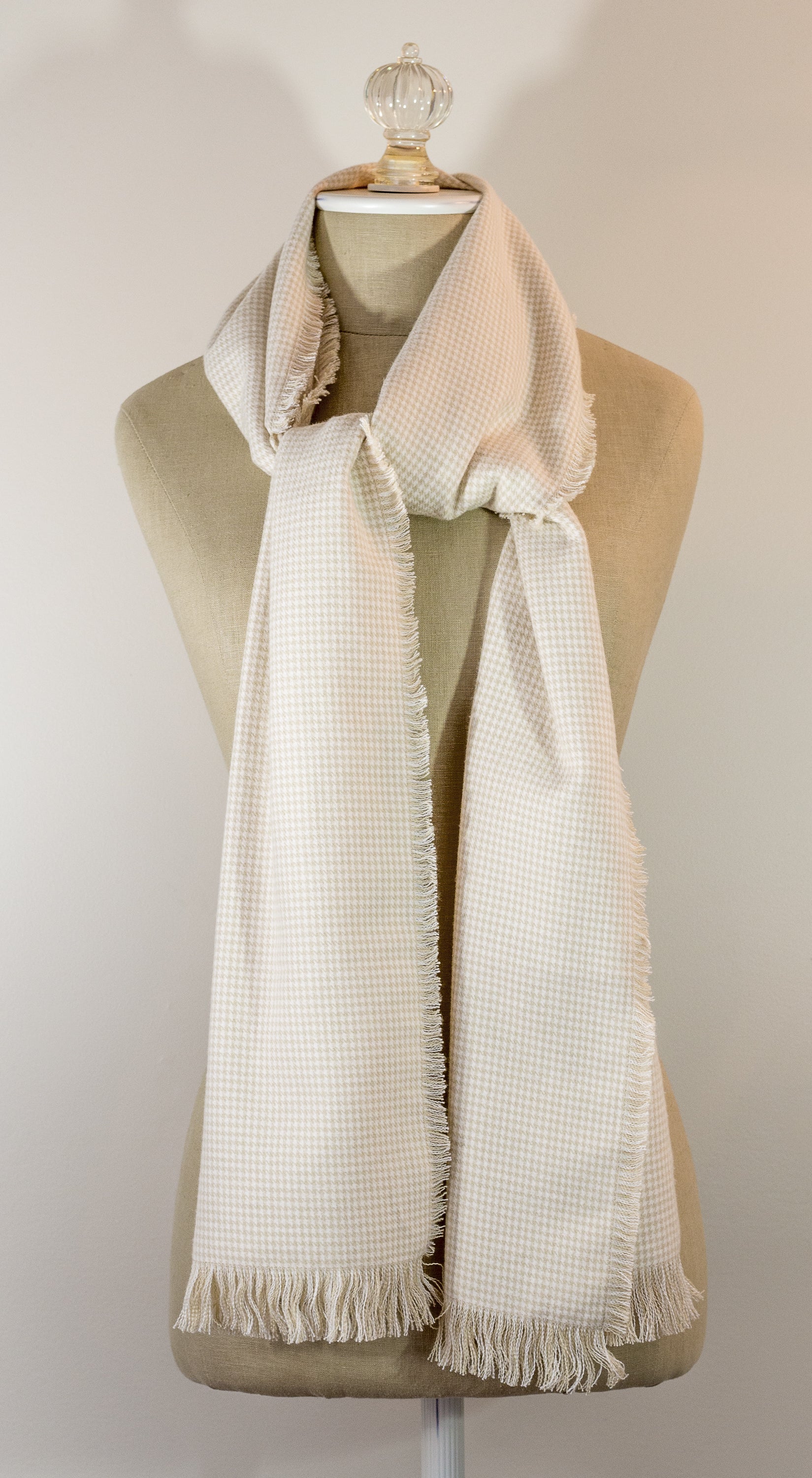 A beige houndstooth flannel scarf displayed on a mannequin, fringed on all sides.
Photo by TheSurgeonsKnots.com [image_link]
