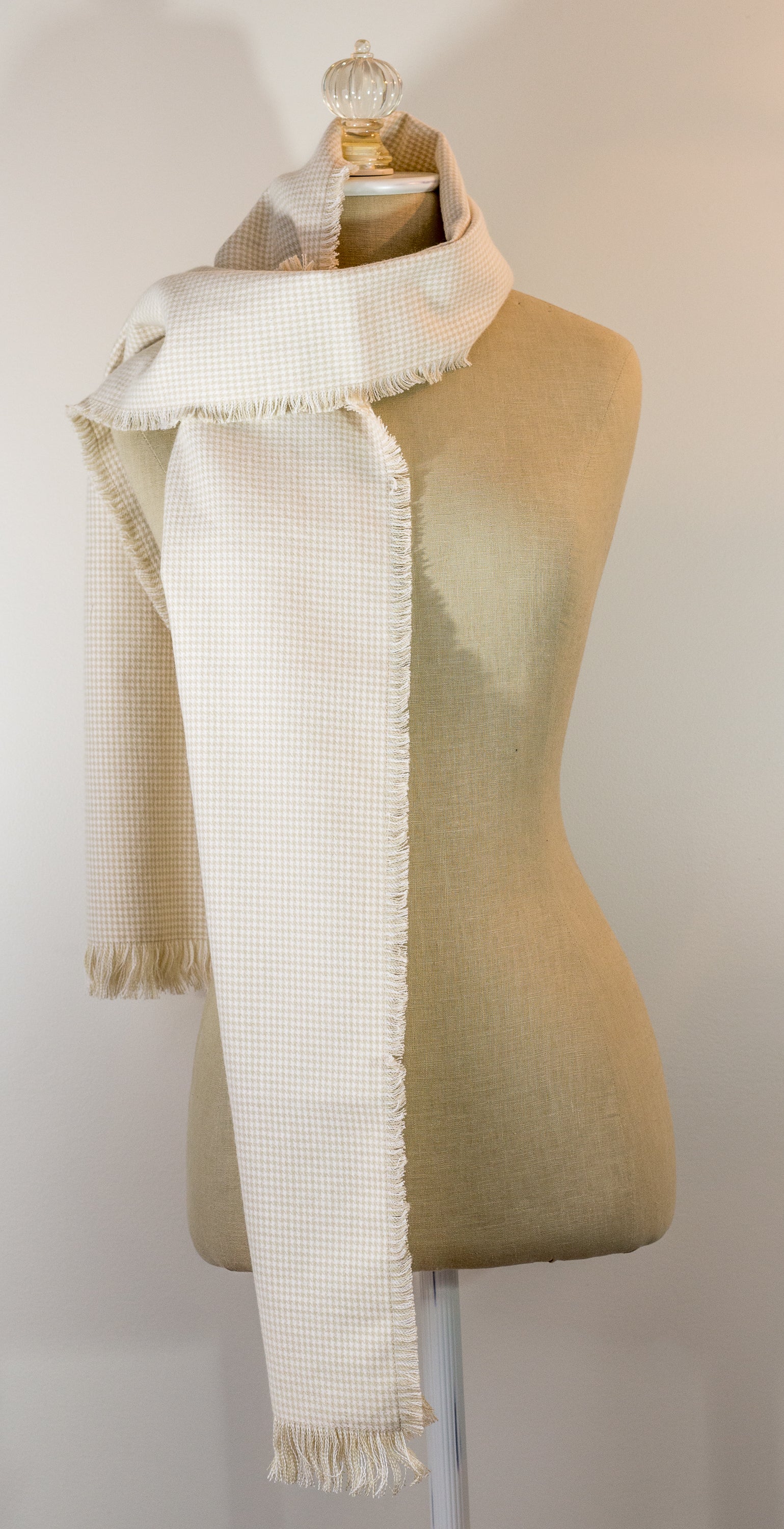 A beige houndstooth flannel scarf displayed on a mannequin, fringed on all sides.
Photo by TheSurgeonsKnots.com [additional_image_link]
