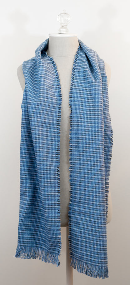 A blue tartan plaid flannel scarf displayed on a mannequin, with fringe detailing on the ends.
Photo by Karen King [additional_image_link]