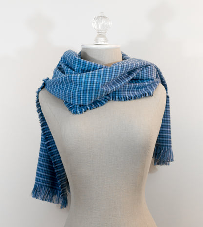 A blue tartan plaid flannel scarf displayed on a mannequin, with fringe detailing on the ends.
Photo by Karen King [additional_image_link]