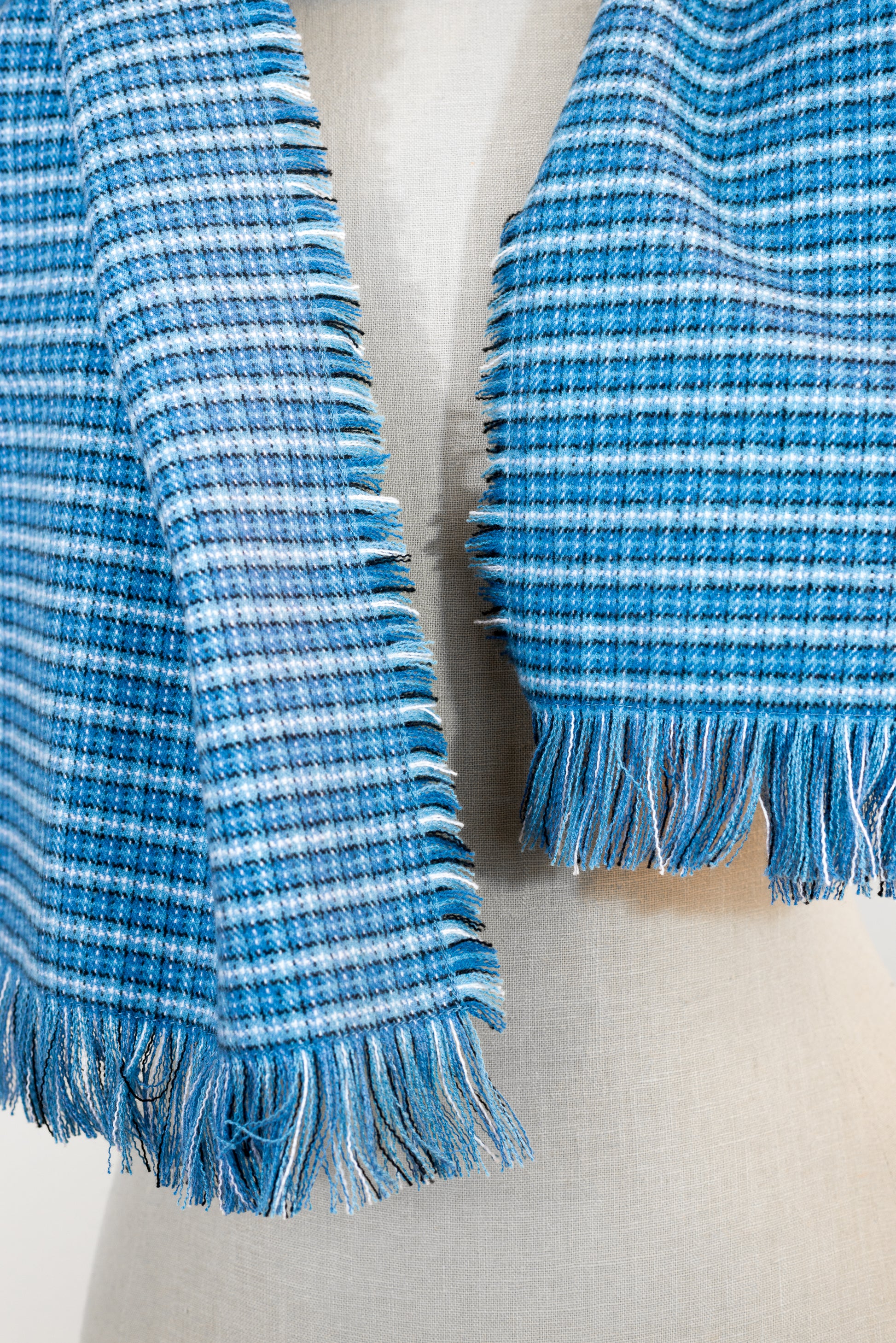 A blue tartan plaid flannel scarf displayed on a mannequin, with fringe detailing on the ends.
Photo by Karen King [additional_image_link]