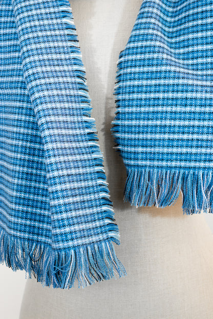 A blue tartan plaid flannel scarf displayed on a mannequin, with fringe detailing on the ends.
Photo by Karen King [additional_image_link]