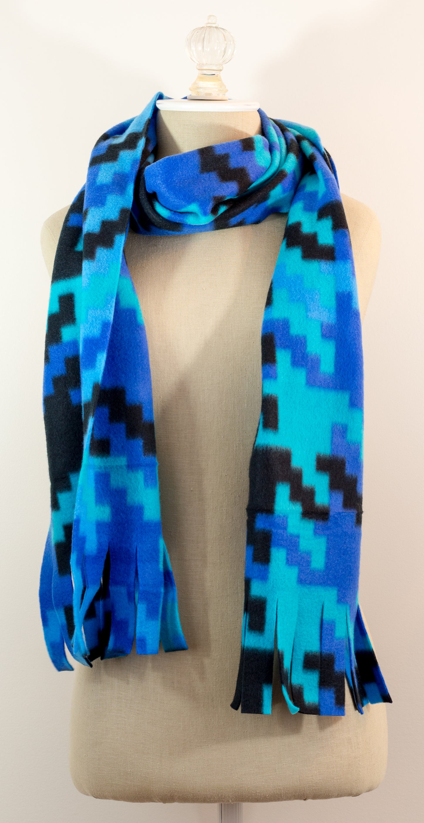 A scarf with a geometric houndstooth pattern in shades of blue and black, displayed on a mannequin.
Photo by Karen King [additional_image_link]
