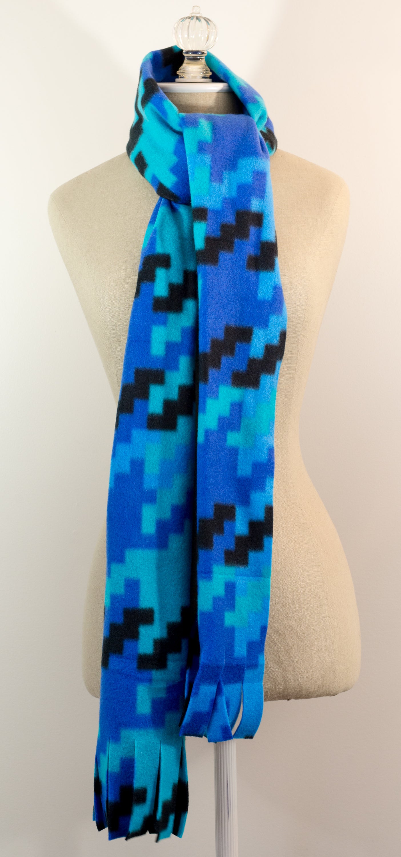 A scarf with a geometric houndstooth pattern in shades of blue and black, displayed on a mannequin.
Photo by Karen King [additional_image_link]