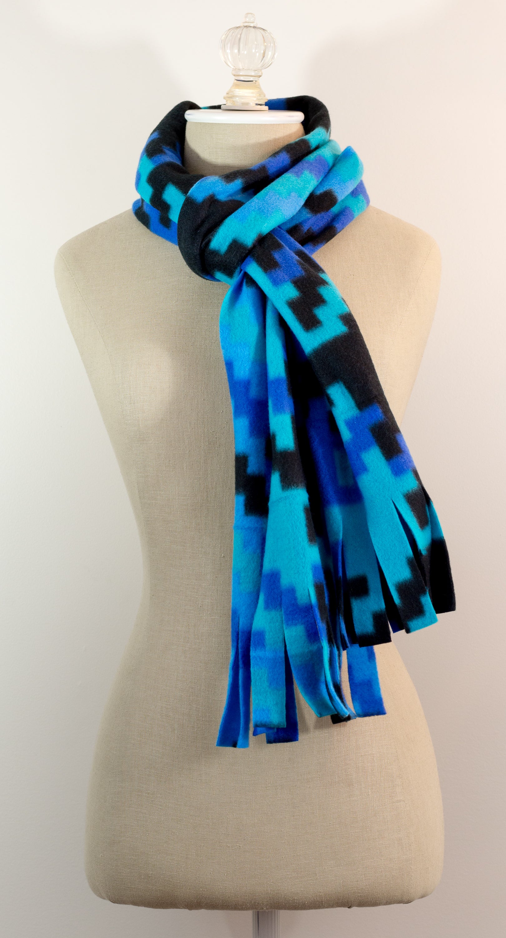 A scarf with a geometric houndstooth pattern in shades of blue and black, displayed on a mannequin.
Photo by Karen King [additional_image_link]