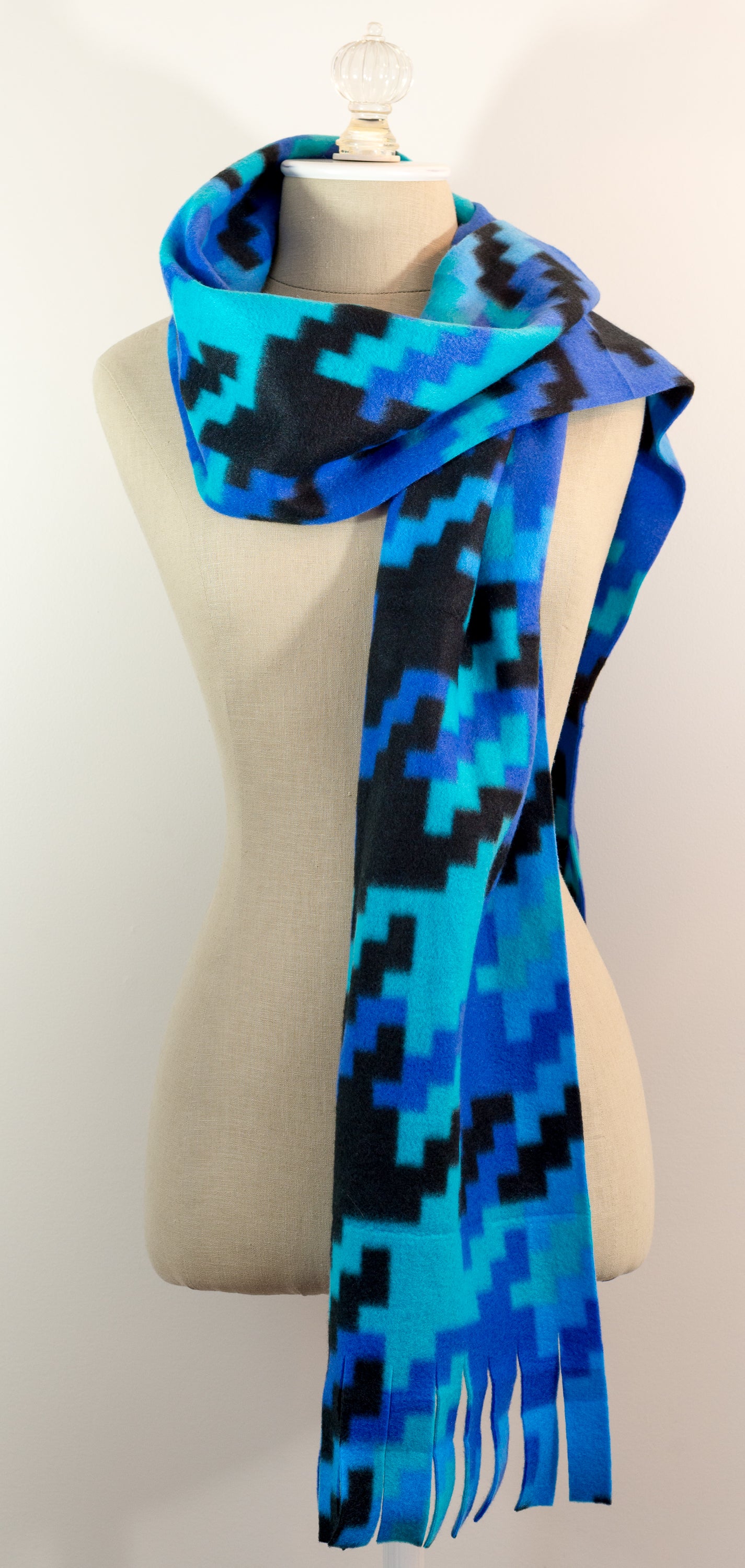 A scarf with a geometric houndstooth pattern in shades of blue and black, displayed on a mannequin.
Photo by Karen King [additional_image_link]