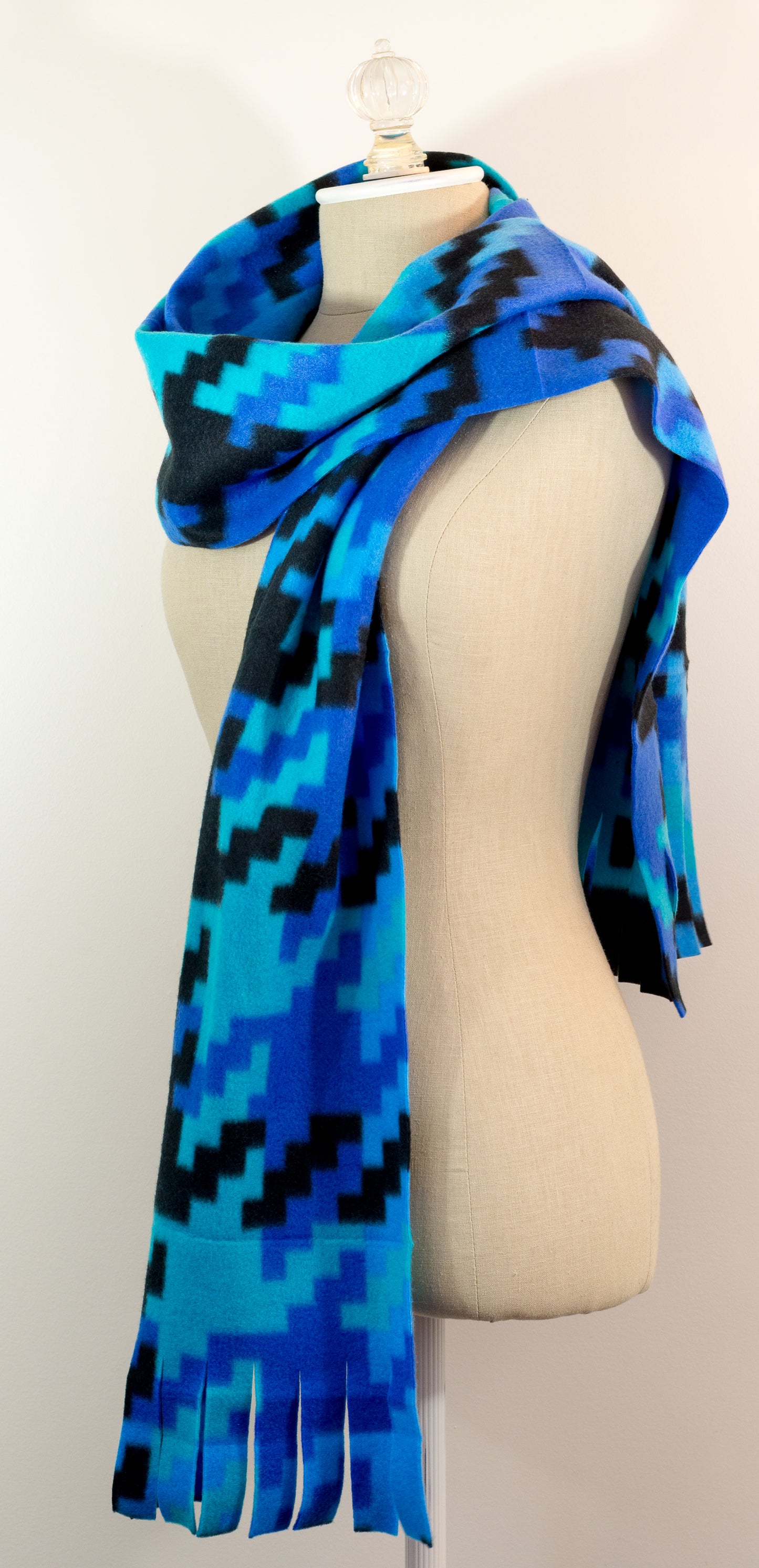 A scarf with a geometric houndstooth pattern in shades of blue and black, displayed on a mannequin.
Photo by Karen King [additional_image_link]