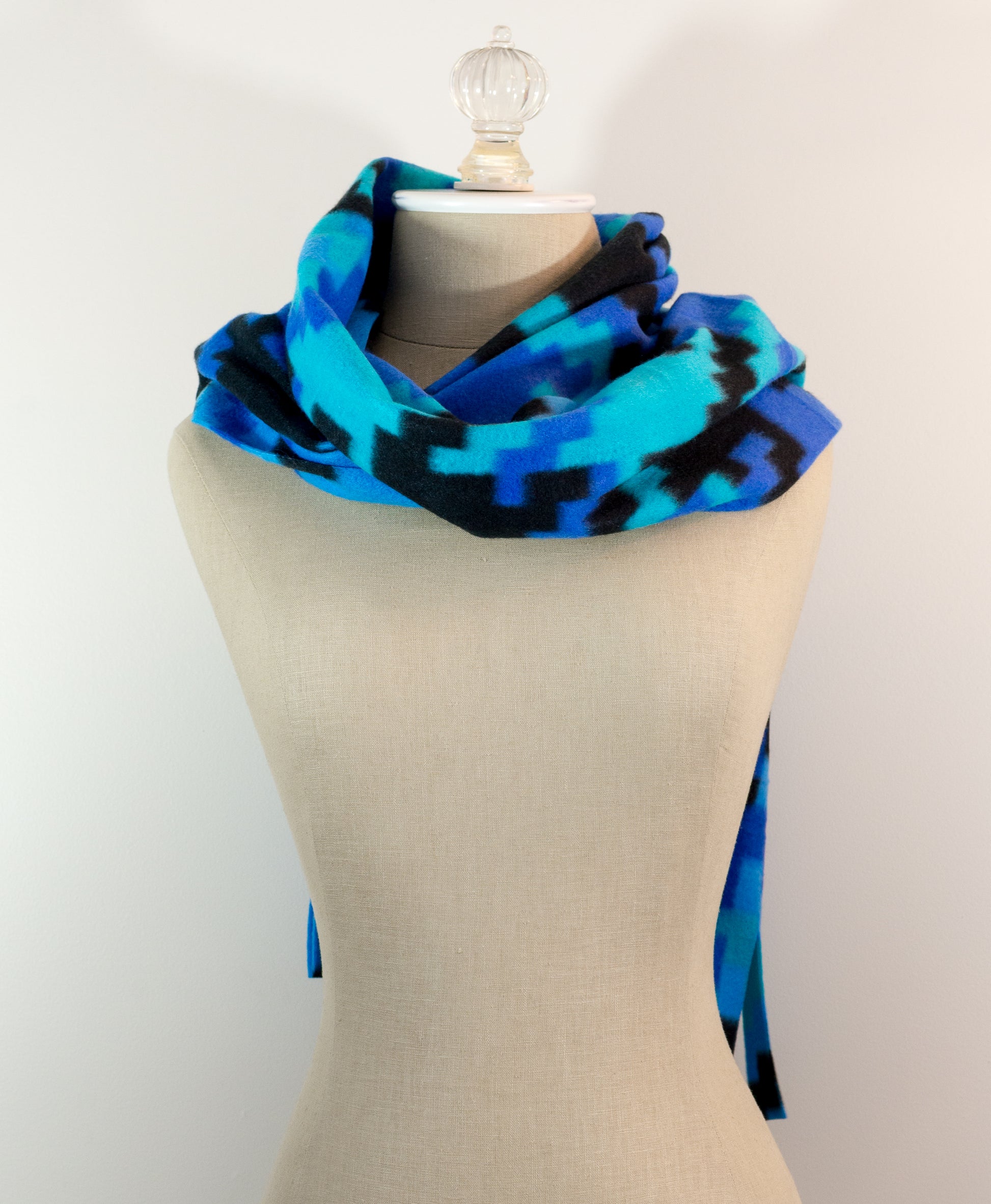 A scarf with a geometric houndstooth pattern in shades of blue and black, displayed on a mannequin.
Photo by Karen King [additional_image_link]