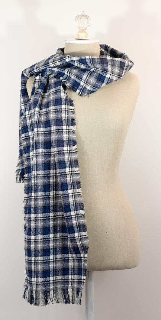 A navy blue, white, and gray plaid scarf with fringe details, draped on a cream-colored mannequin torso against a plain white background.
Photo by Karen King [image_link]