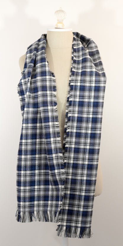 A navy blue, white, and gray plaid scarf with fringe details, draped on a cream-colored mannequin torso against a plain white background.
Photo by Karen King [additional_image_link]