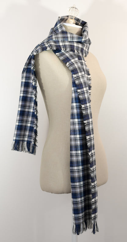 A navy blue, white, and gray plaid scarf with fringe details, draped on a cream-colored mannequin torso against a plain white background.
Photo by Karen King [additional_image_link]
