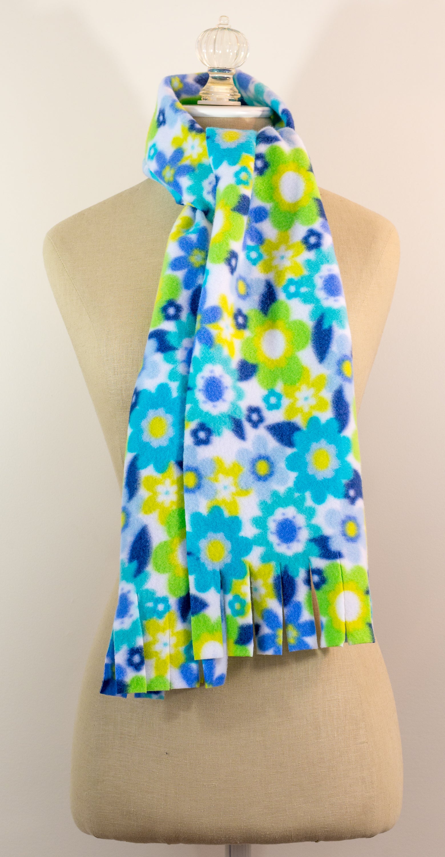 A blue and yellow floral polar fleece scarf with fringe displayed on a mannequin.
Photo by Karen King [image_link]
