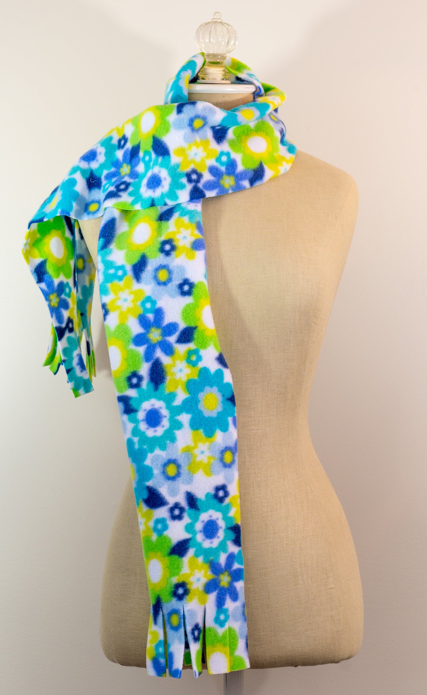 A blue and yellow floral polar fleece scarf with fringe displayed on a mannequin.
Photo by Karen King [additional_image_link]