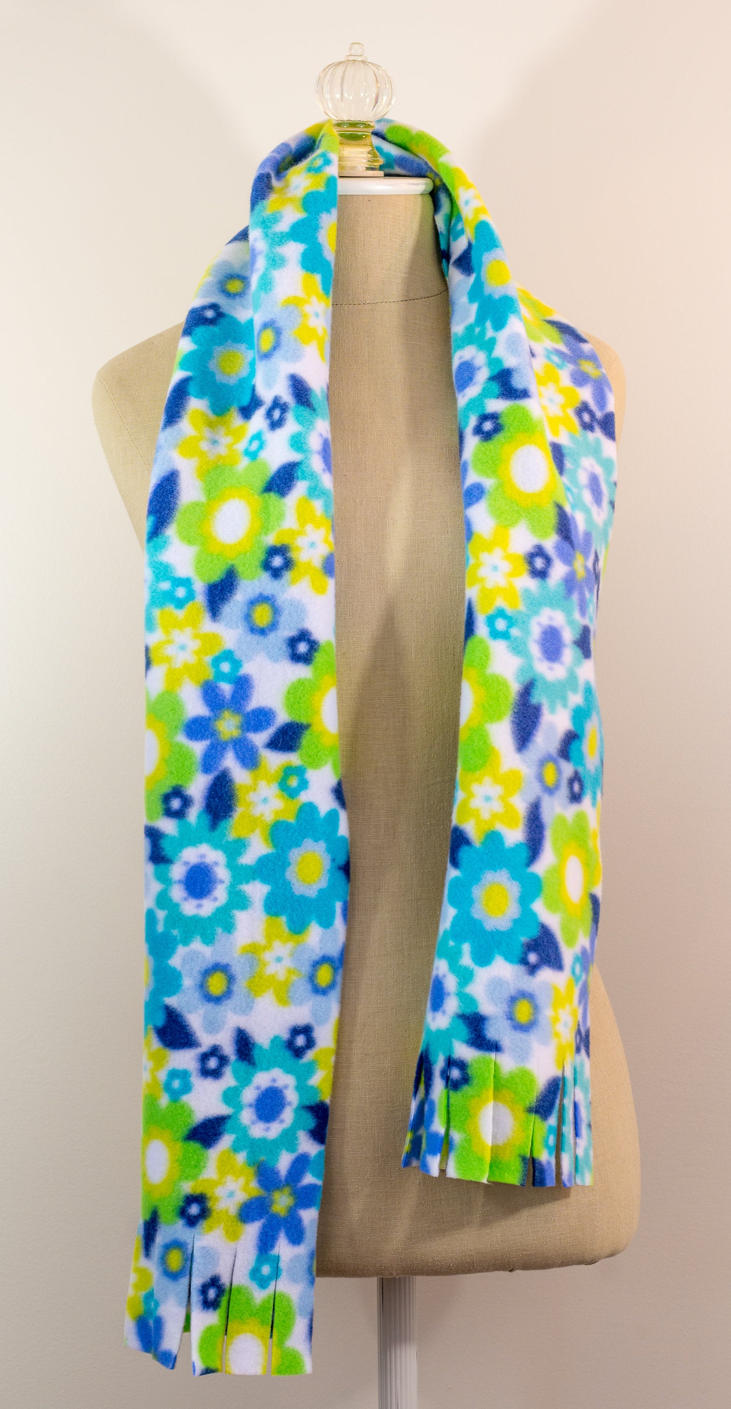 A blue and yellow floral polar fleece scarf with fringe displayed on a mannequin.
Photo by Karen King [additional_image_link]