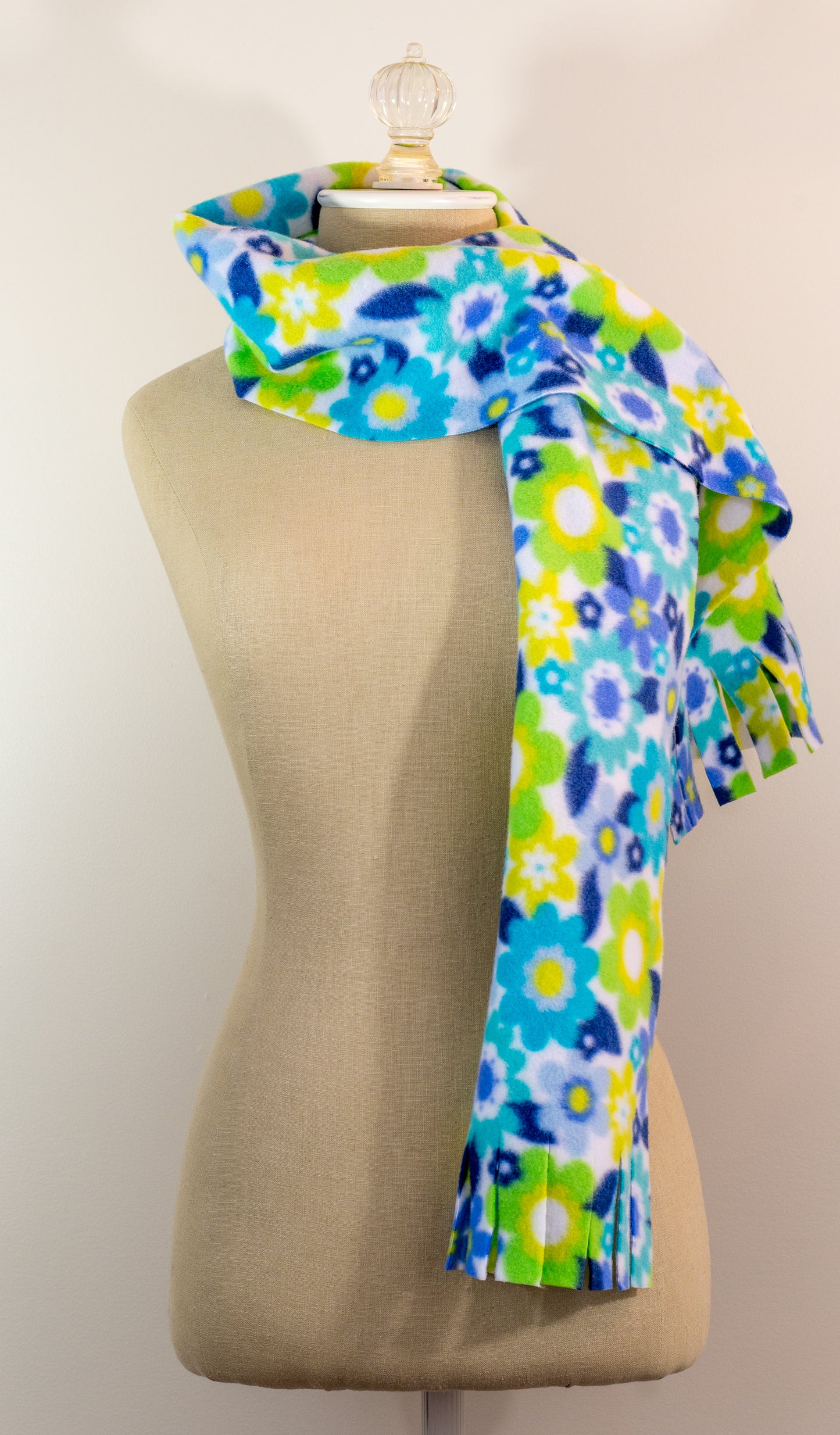 A blue and yellow floral polar fleece scarf with fringe displayed on a mannequin.
Photo by Karen King [additional_image_link]