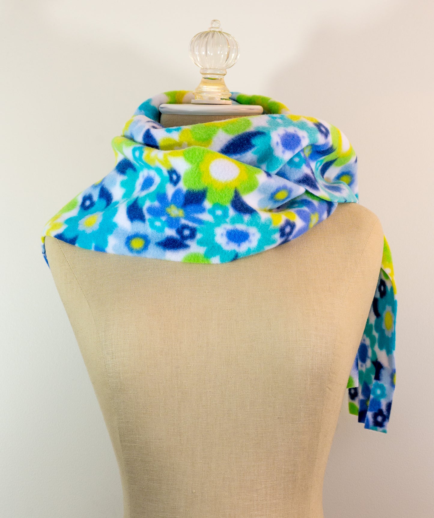 A blue and yellow floral polar fleece scarf with fringe displayed on a mannequin.
Photo by Karen King [additional_image_link]