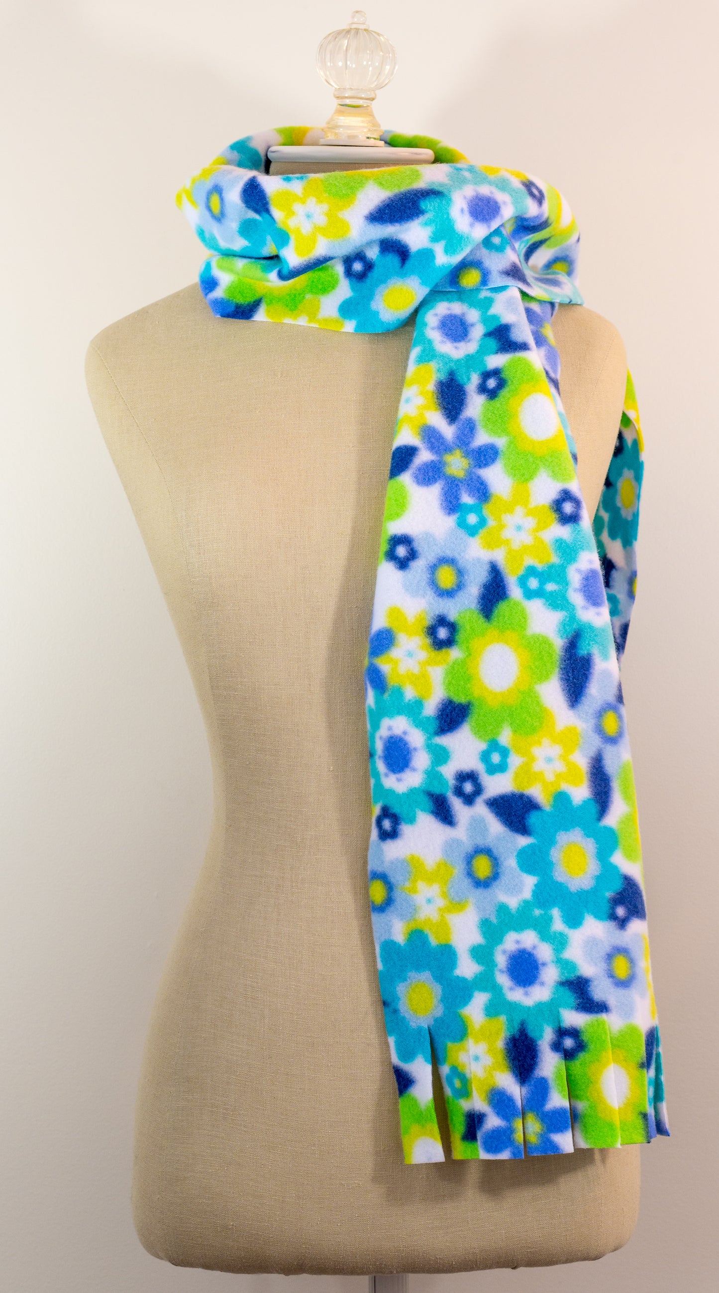 A blue and yellow floral polar fleece scarf with fringe displayed on a mannequin.
Photo by Karen King [additional_image_link]