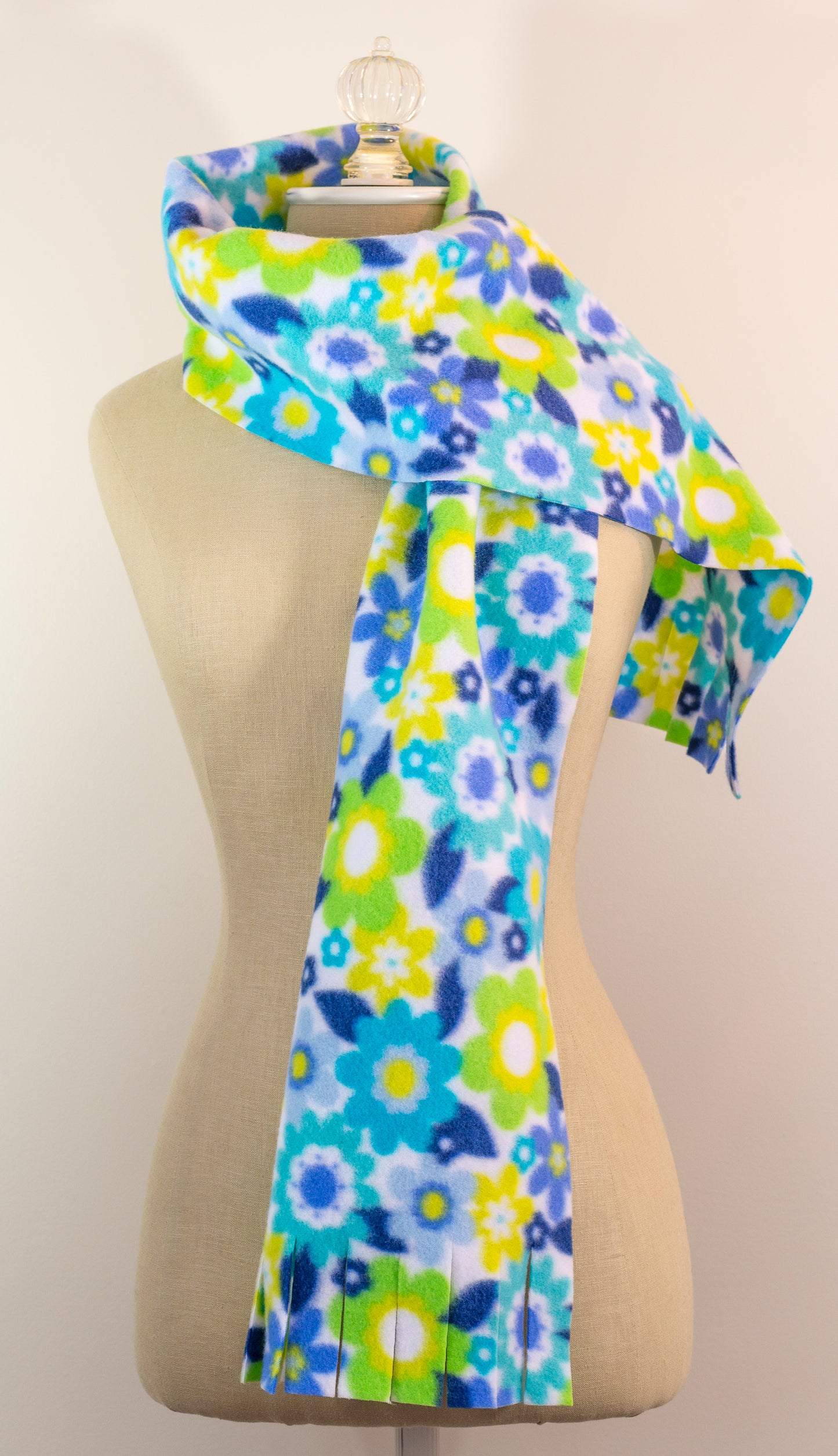 A blue and yellow floral polar fleece scarf with fringe displayed on a mannequin.
Photo by Karen King [additional_image_link]
