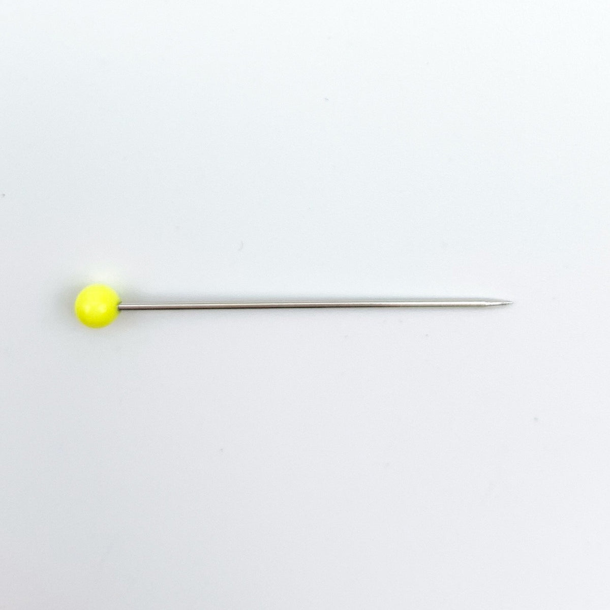 A single straight pin with a bright yellow spherical head and a thin metallic shaft, placed horizontally on a plain white background.
Photo by Bohin [additional_image_link]