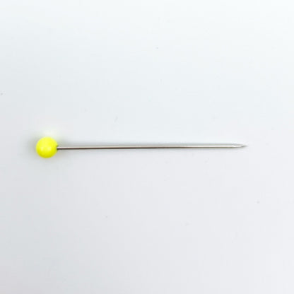 A single straight pin with a bright yellow spherical head and a thin metallic shaft, placed horizontally on a plain white background.
Photo by Bohin [additional_image_link]
