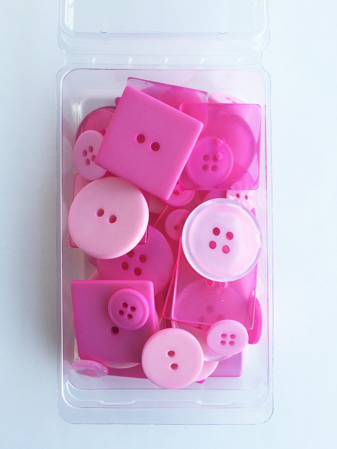 A clear plastic container holding 55 bubblegum pink buttons of various sizes, from 1/4in to 1 1/8in, for crafting and sewing projects.
Photo by JustAnotherButtonCompany.com [image_link]