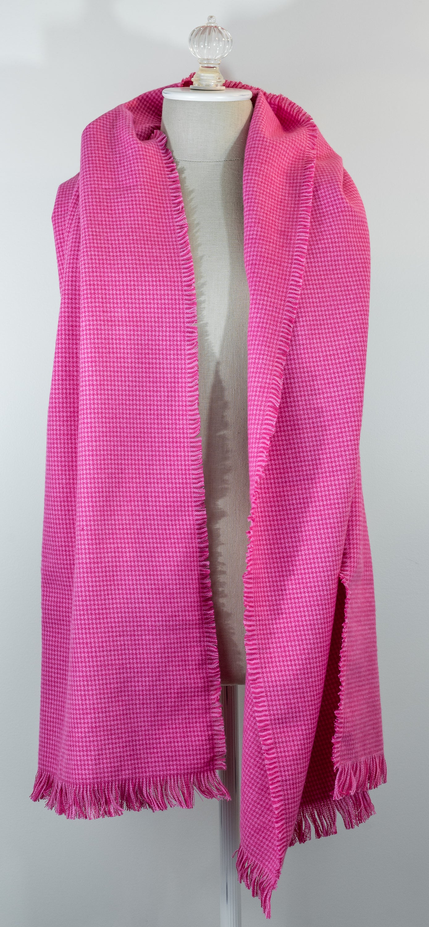 A bubblegum pink houndstooth flannel shawl with a fringe, displayed on a mannequin.
Photo by Karen King [additional_image_link]