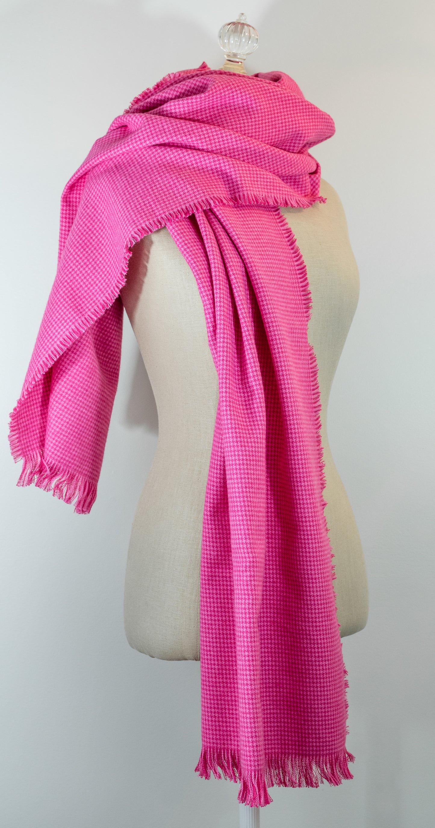 A bubblegum pink houndstooth flannel shawl with a fringe, displayed on a mannequin.
Photo by Karen King [image_link]