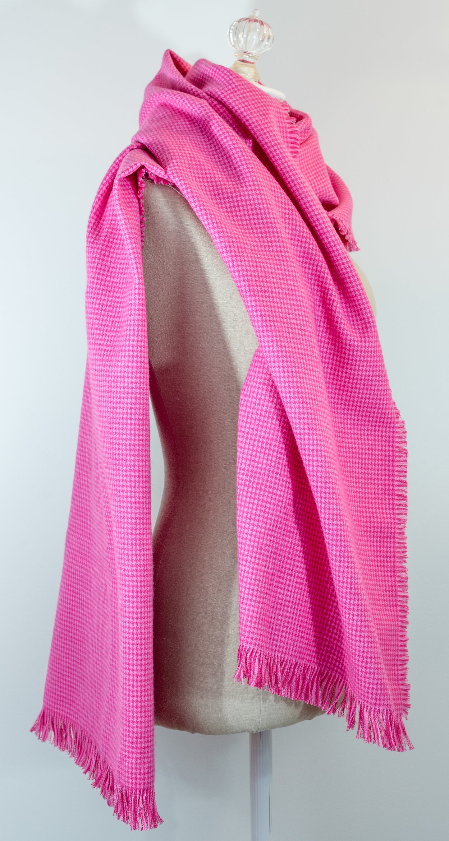 A bubblegum pink houndstooth flannel shawl with a fringe, displayed on a mannequin.
Photo by Karen King [additional_image_link]