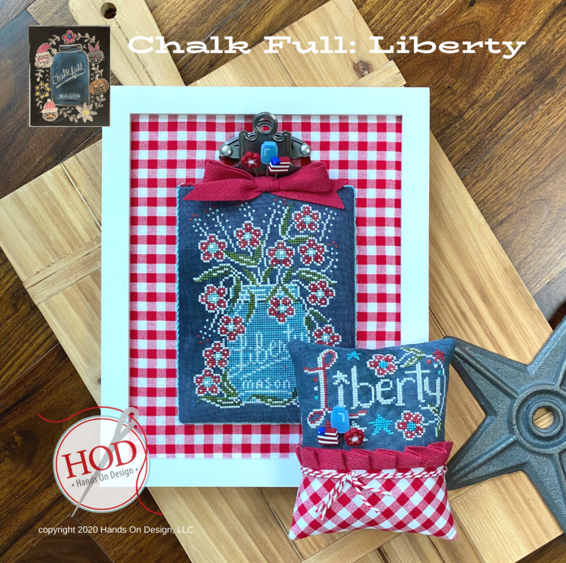 A handmade chalkboard-style decorative piece and matching fabric pouch displayed on a wooden surface. The chalkboard has a red-and-white gingham border, a blue center with floral embroidery, and a red bow at the top.
Photo by HandsOnDesign.biz [image_link]
