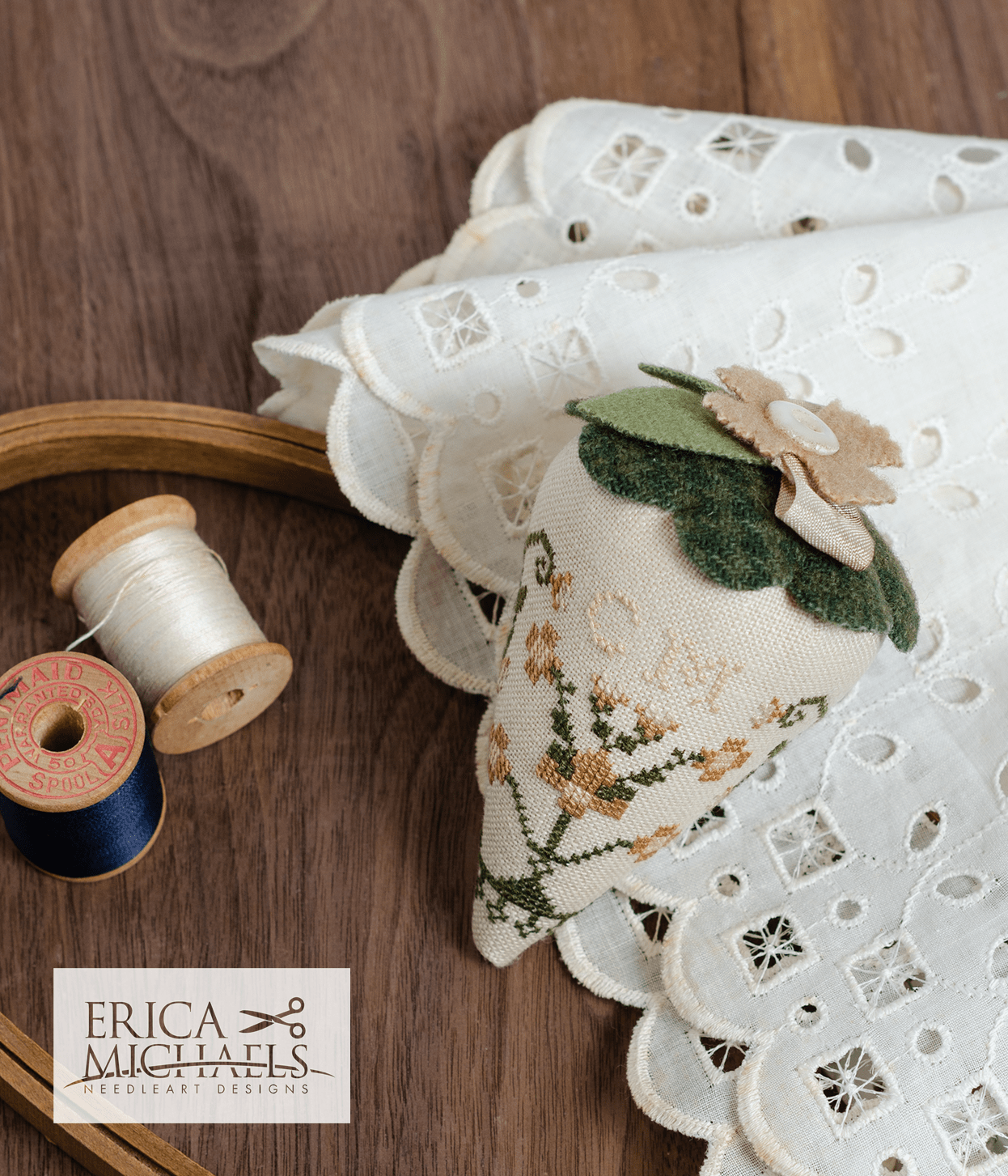 One linen cross stitch pincushions with floral embroidery designs, accompanied by a spool of linen thread, a needle, and buttons.
Photos by Erica Michaels [additional_image_link]