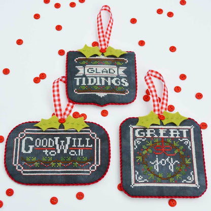 Three cross-stitched Christmas ornaments 'Glad Tidings' Goodwill to all' and ' Great joy' with festive sayings on a white background with red berries.
Photo by HandsOnDesign.biz [image_link]