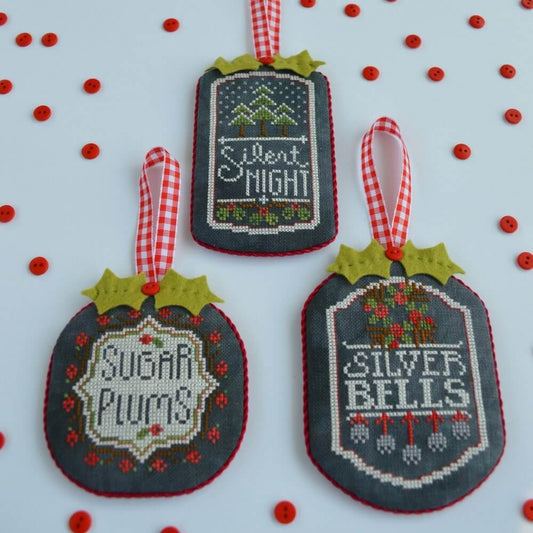 Three cross-stitched Christmas ornaments with festive texts 'Silent Night' 'Sugar Plums' and 'Silver Bells' and designs are on a white background.
Photo by HandsOnDesign.biz [image_link]