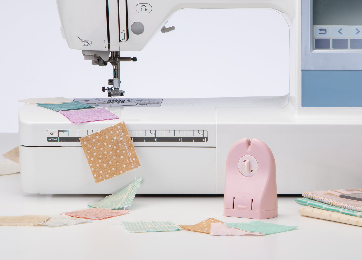 Sewing machine with fabric pieces and a pink presser foot on a white background
Photo by Clover-USA.com [additional_image_link]