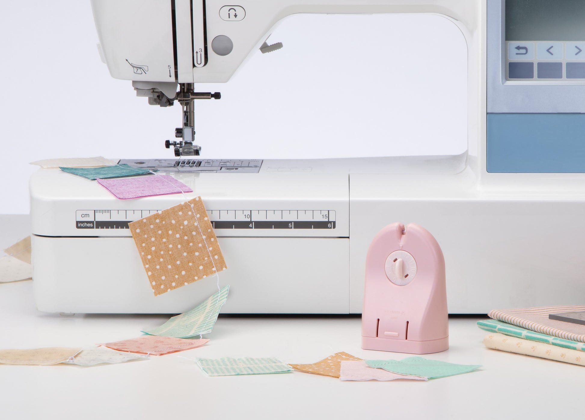 Sewing machine with fabric pieces and a pink presser foot on a white background
Photo by Clover-USA.com [additional_image_link]